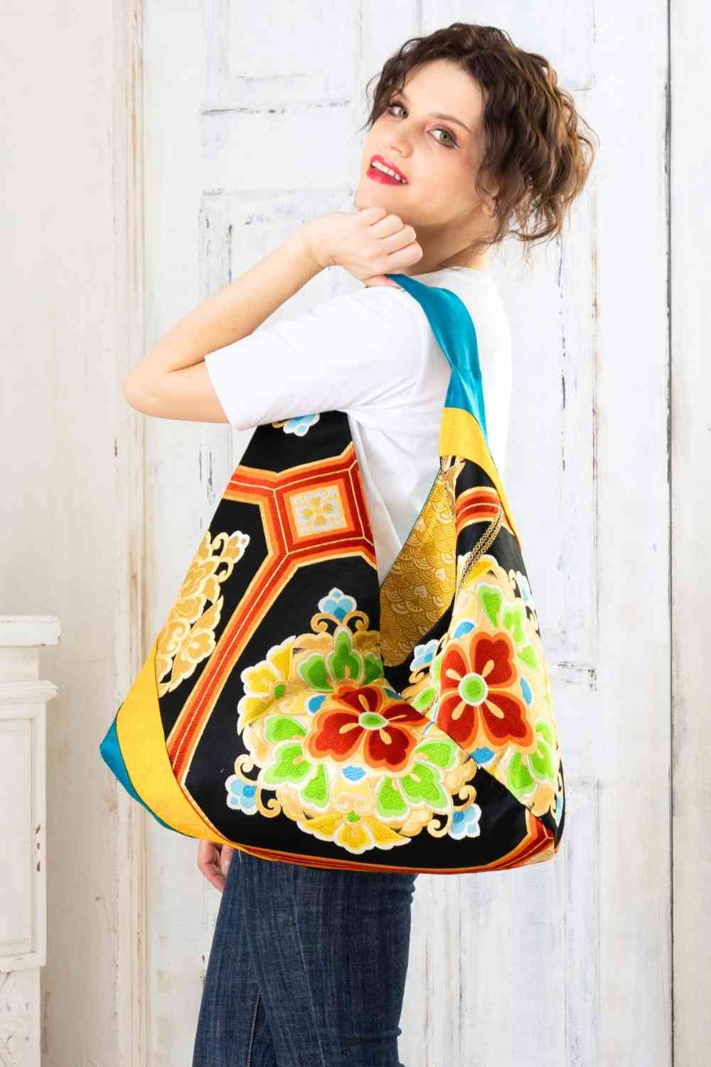 A pictue of a woman carrying a boho bag. With this oversized bag, she is making a bold fashion statement. The intricate details on this embroidered boho bag are a testament to its unique charm and the large boho bag trend. It's a vibrant accessory that elevates her style and captures attention wherever she goes.