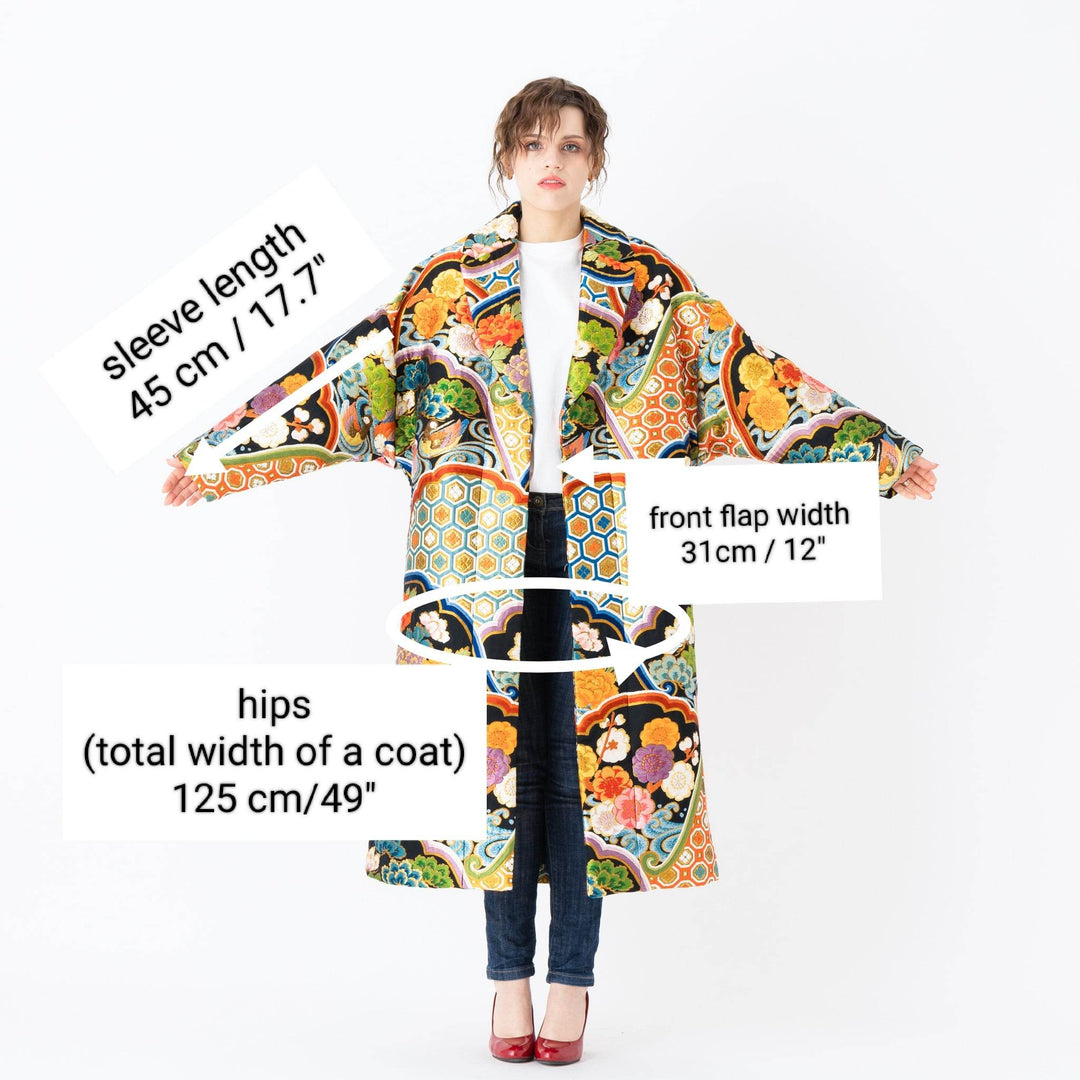 A woman is wearing an oversized silk coat for women. This long silk coat embodies the essence of a long coat for women. Its surface is adorned with intricate silk embroidery, exemplifying the artistry behind a silk embroidered coat for women. The coat's length accentuates its elegance, making it a perfect representation of a long embroidered coat. The oversized nature of this oversized coat for women adds a touch of grandeur to the ensemble, combining style and comfort seamlessly.