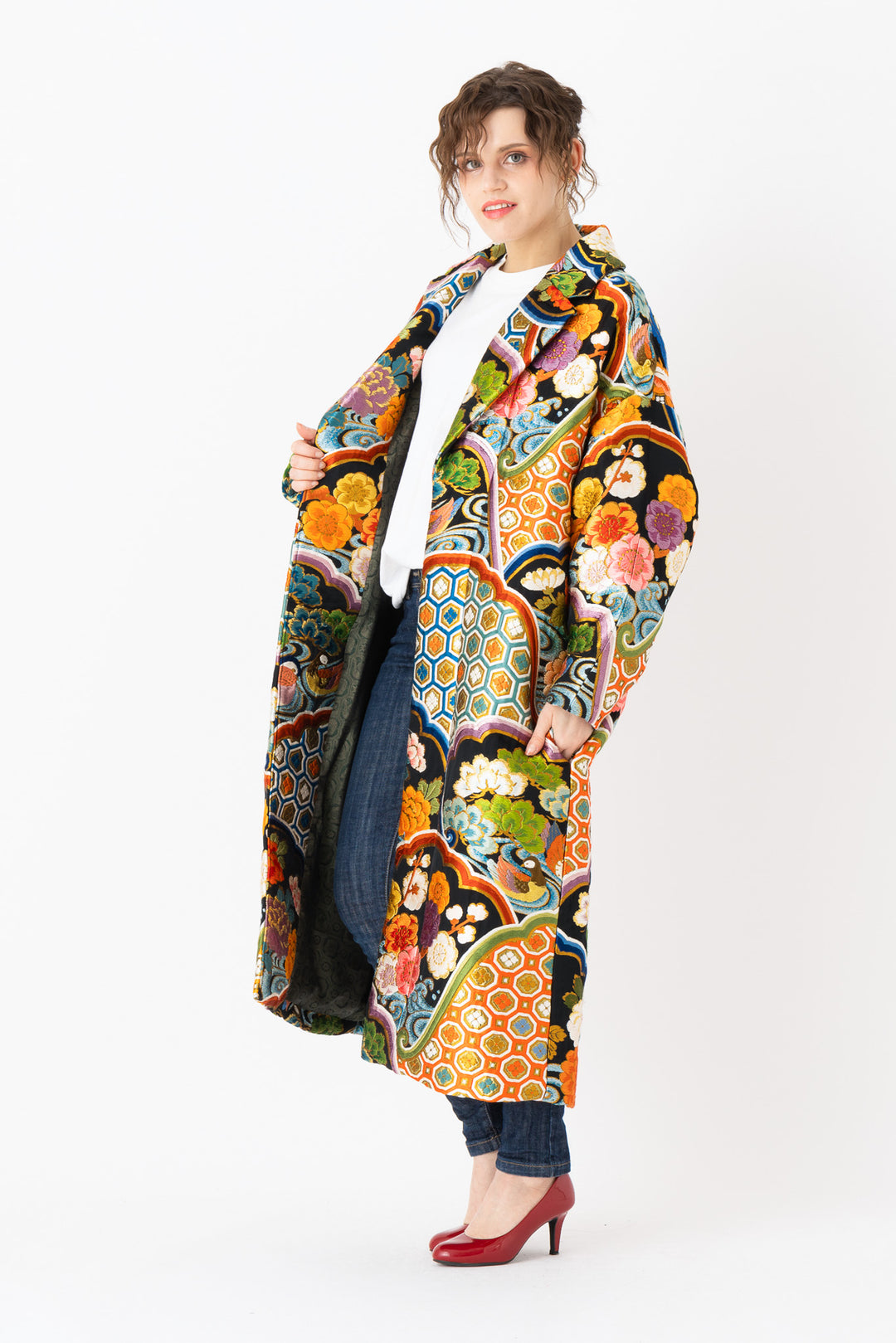 A woman is wearing an oversized silk coat for women. This long silk coat embodies the essence of a long coat for women. Its surface is adorned with intricate silk embroidery, exemplifying the artistry behind a silk embroidered coat for women. The coat's length accentuates its elegance, making it a perfect representation of a long embroidered coat. The oversized nature of this oversized coat for women adds a touch of grandeur to the ensemble, combining style and comfort seamlessly.