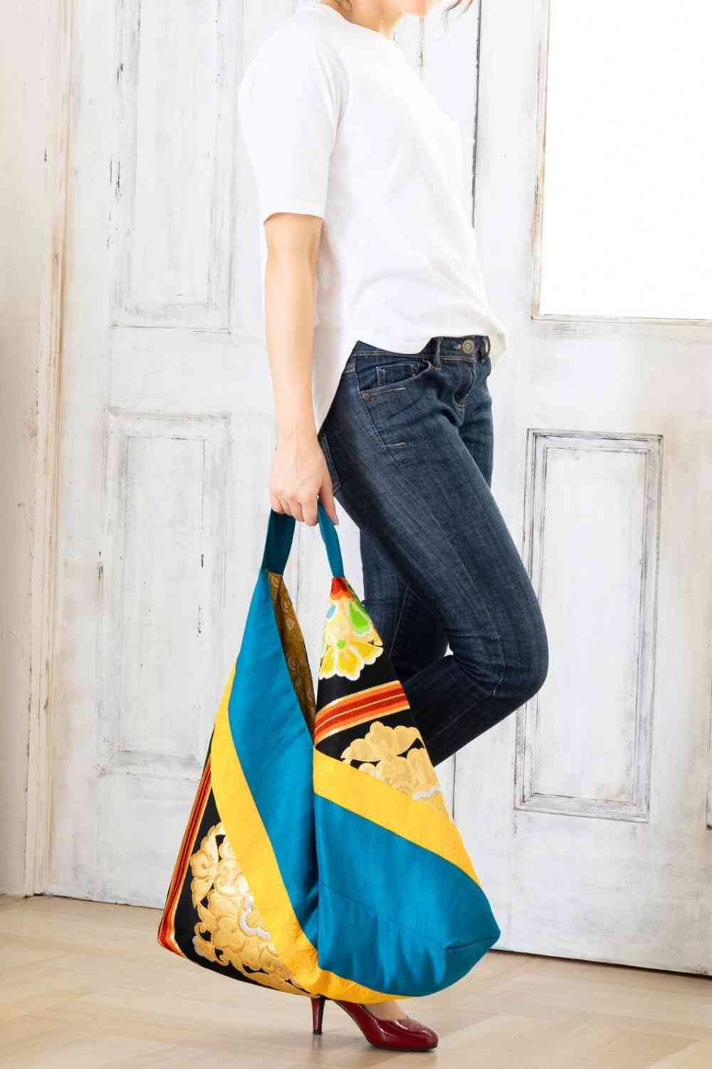 A pictue of a woman carrying a boho bag. With this oversized bag, she is making a bold fashion statement. The intricate details on this embroidered boho bag are a testament to its unique charm and the large boho bag trend. It's a vibrant accessory that elevates her style and captures attention wherever she goes.