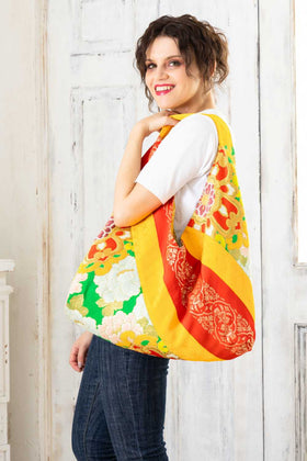 A pictue of a woman carrying a boho bag. With this oversized bag, she is making a bold fashion statement. The intricate details on this embroidered boho bag are a testament to its unique charm and the large boho bag trend. It's a vibrant accessory that elevates her style and captures attention wherever she goes.
