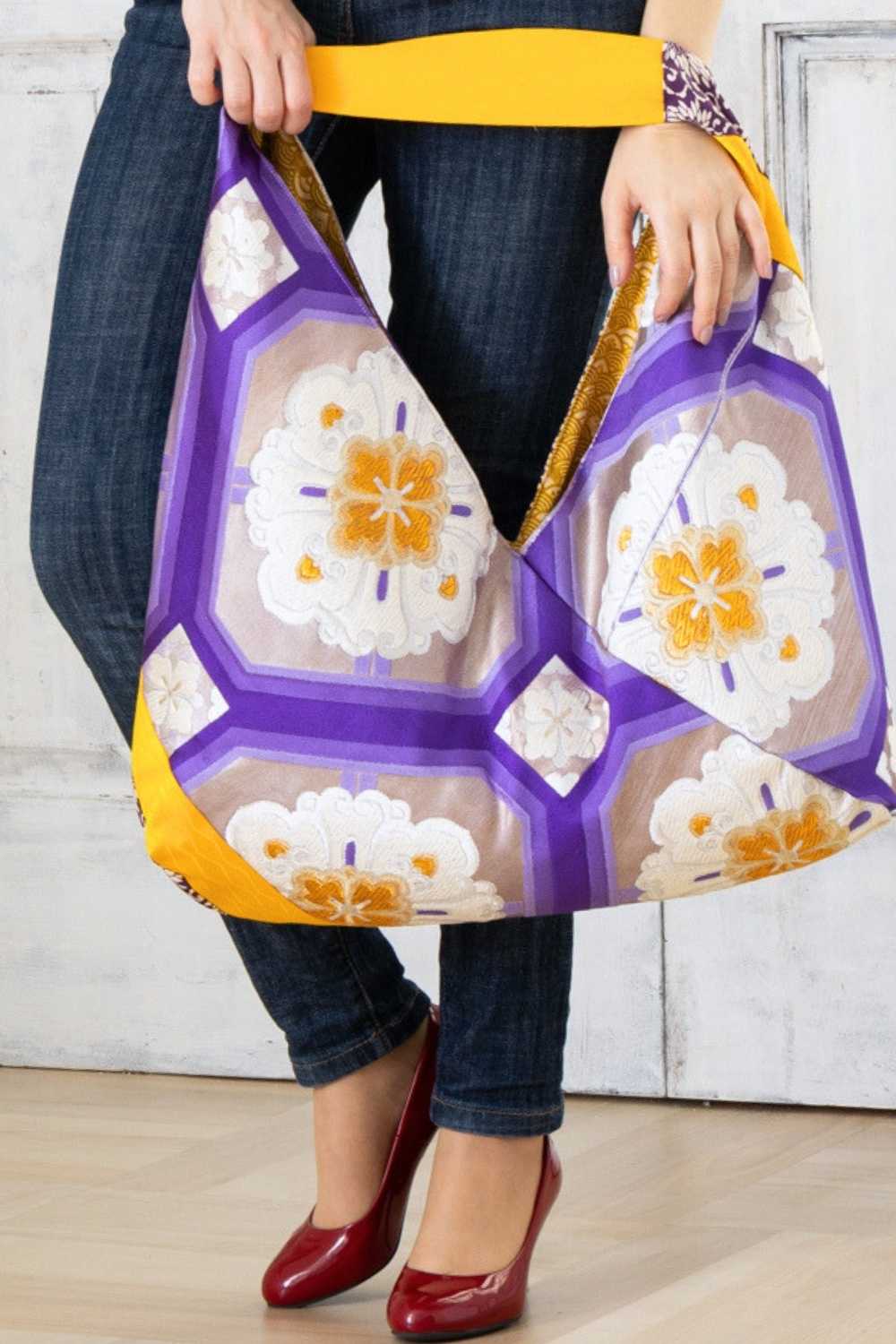 A pictue of a woman carrying a boho bag. With this oversized bag, she is making a bold fashion statement. The intricate details on this embroidered boho bag are a testament to its unique charm and the large boho bag trend. It's a vibrant accessory that elevates her style and captures attention wherever she goes.