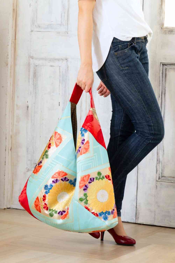 A pictue of a woman carrying a boho bag. With this oversized bag, she is making a bold fashion statement. The intricate details on this embroidered boho bag are a testament to its unique charm and the large boho bag trend. It's a vibrant accessory that elevates her style and captures attention wherever she goes.