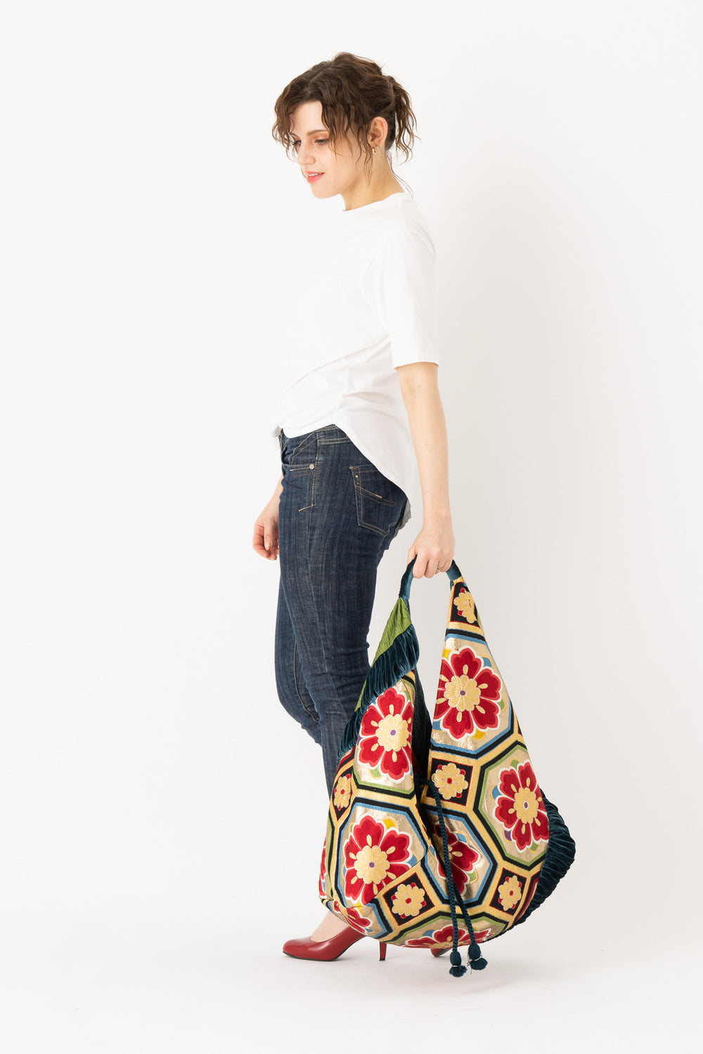 A woman is carrying a stunning embroidered boho bag, showcasing the intricate details on this large tote bag. This large boho bag elevates her style and is an example of embroidered tote bag styling.