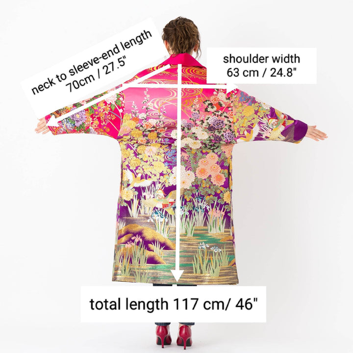 A woman is wearing an oversized silk coat for women. This long silk coat embodies the essence of a long coat for women. Its surface is adorned with intricate silk embroidery, exemplifying the artistry behind a silk embroidered coat for women. The coat's length accentuates its elegance, making it a perfect representation of a long embroidered coat. The oversized nature of this oversized coat for women adds a touch of grandeur to the ensemble, combining style and comfort seamlessly. 