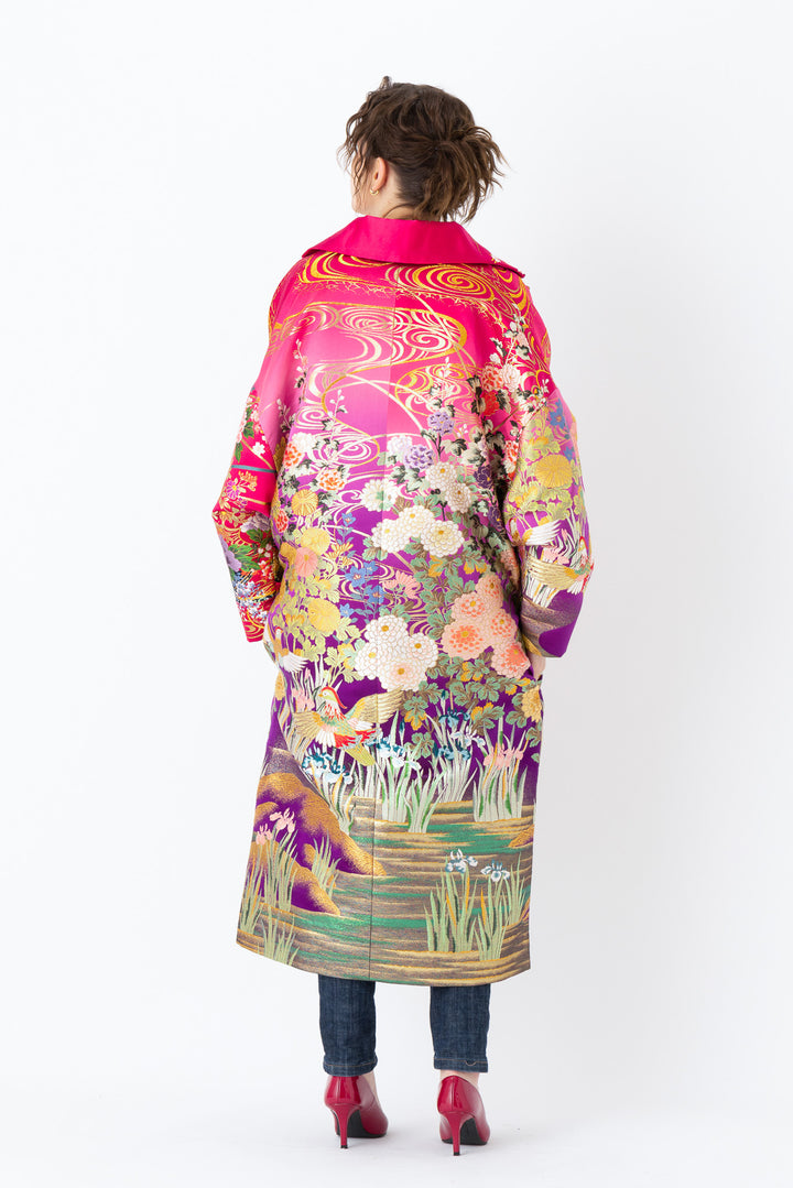 A woman is wearing an oversized silk coat for women. This long silk coat embodies the essence of a long coat for women. Its surface is adorned with intricate silk embroidery, exemplifying the artistry behind a silk embroidered coat for women. The coat's length accentuates its elegance, making it a perfect representation of a long embroidered coat. The oversized nature of this oversized coat for women adds a touch of grandeur to the ensemble, combining style and comfort seamlessly. 