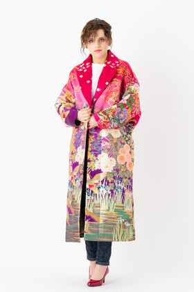 A woman is wearing an oversized silk coat for women. This long silk coat embodies the essence of a long coat for women. Its surface is adorned with intricate silk embroidery, exemplifying the artistry behind a silk embroidered coat for women. The coat's length accentuates its elegance, making it a perfect representation of a long embroidered coat. The oversized nature of this oversized coat for women adds a touch of grandeur to the ensemble, combining style and comfort seamlessly. 