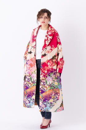 A woman is wearing an oversized silk coat for women. This long silk coat embodies the essence of a long coat for women. Its surface is adorned with intricate silk embroidery, exemplifying the artistry behind a silk embroidered coat for women. The coat's length accentuates its elegance, making it a perfect representation of a long embroidered coat. The oversized nature of this oversized coat for women adds a touch of grandeur to the ensemble, combining style and comfort seamlessly.