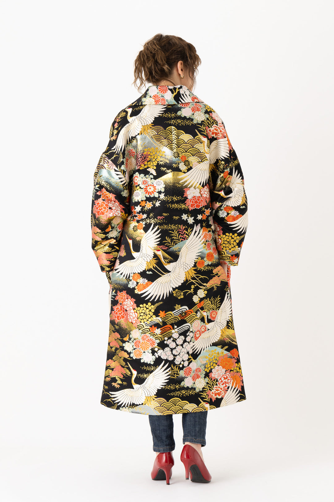 A woman is wearing an oversized silk coat for women. This long silk coat embodies the essence of a long coat for women. Its surface is adorned with intricate silk embroidery, exemplifying the artistry behind a silk embroidered coat for women. The coat's length accentuates its elegance, making it a perfect representation of a long embroidered coat. The oversized nature of this oversized coat for women adds a touch of grandeur to the ensemble, combining style and comfort seamlessly. 